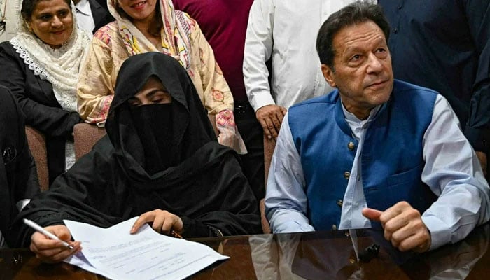 Imran Khan (right), along with his wife Bushra Bibi (left), looks on as she signs surety bonds for bail in various cases, at a registrar office in the Lahore High Court on July 17, 2023. — AFP