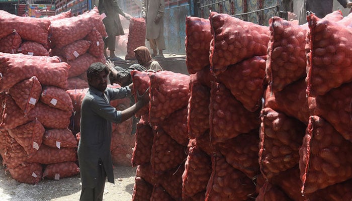Pakistani labourers unload potato sacks from a truck at a wholesale vegetable market in Lahore. — AFP/File