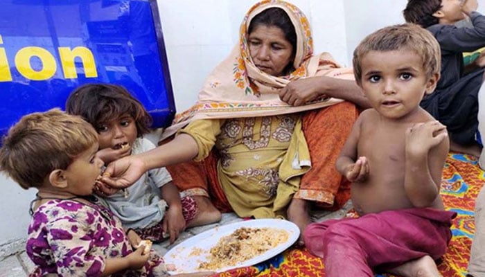 A flood-affected woman feeds her children in Sindh. — APP/File