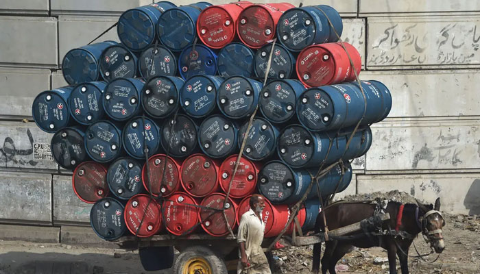 A man stands next to a horsecart laden with oil drums on a street in Lahore. — AFP/File
