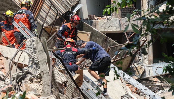 Emergency workers assisting a survivor after he was rescued from a damaged building in New Taipei City. — AFP/File