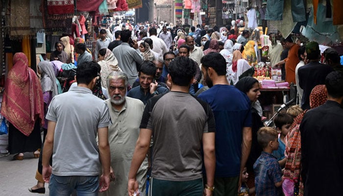 A representational image showing people walking past a market area. — AFP/File