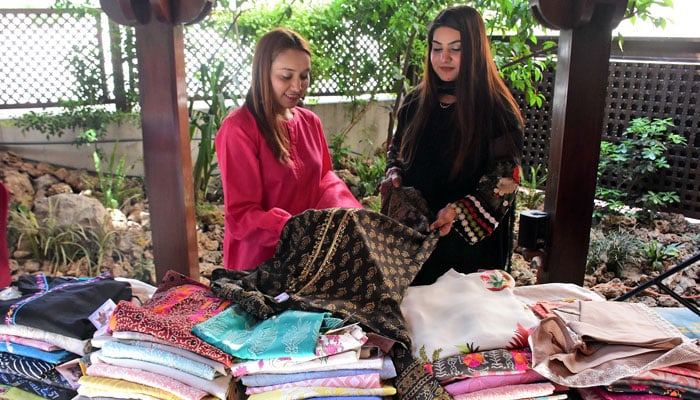 Women are buying handmade clothes on a stall during Eid Bazaar, at a local hotel in Islamabad on April 7, 2024. — Online