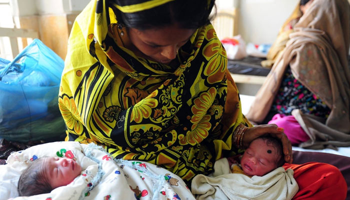 A representational image showing a woman cradling two new-born babies. — AFP/File