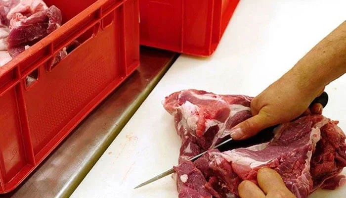 This Image shows a person cutting meat. — AFP/File