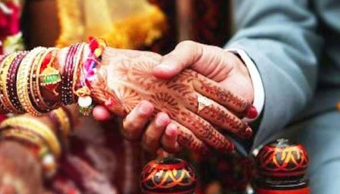This picture shows a groom holding his brides hand. — AFP/File