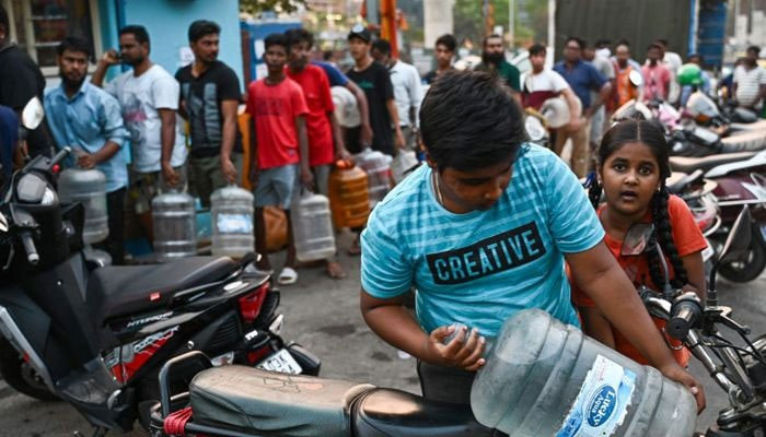People wait in a queue with cans to collect drinking water due to the water crisis in Bengaluru. — AFP/File