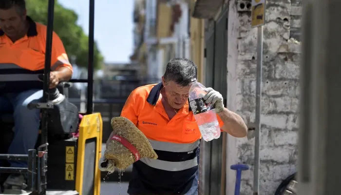 A worker cools off while working in a street during a heatwave on July 17, 2023. — AFP