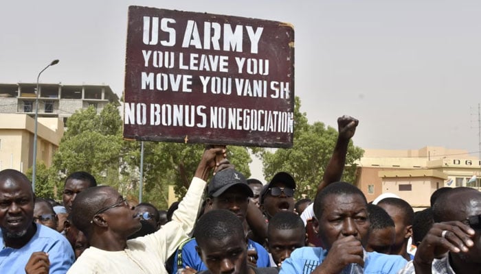 Protesters react as a man holds up a sign demanding U.S. Army soldiers leave Niger without negotiation during a demonstration in Niamey, on April 13, 2024. — AFP