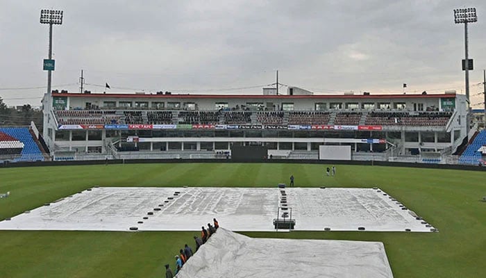 Ground staff members cover the field with a plastic sheet following rain showers at the Rawalpindi Cricket Stadium. — AFP/File