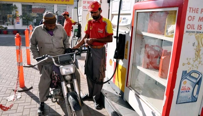 Fuel station worker filling petrol in a motorcycle at a petrol pump. — PPI/File