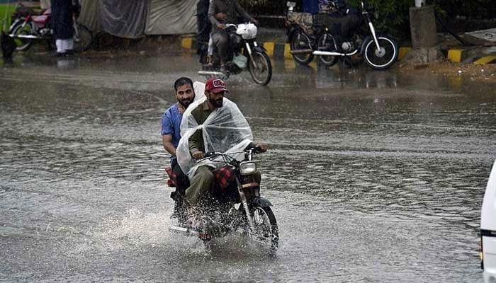 Motorcyclists are passing through a flooded road amid heavy rain.— APP/File