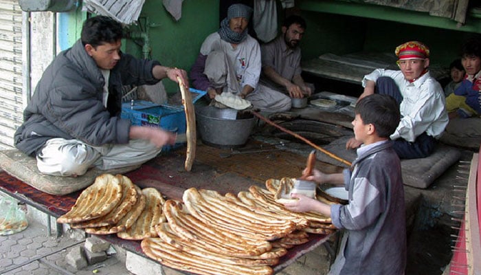 Workers bake roti and naan at a tandoor. — APP/File
