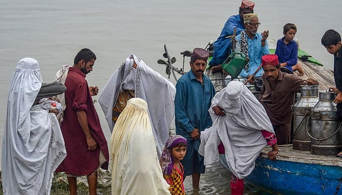 Stranded people are evacuated on boats from flood-affected areas after heavy monsoon rains. — AFP/File