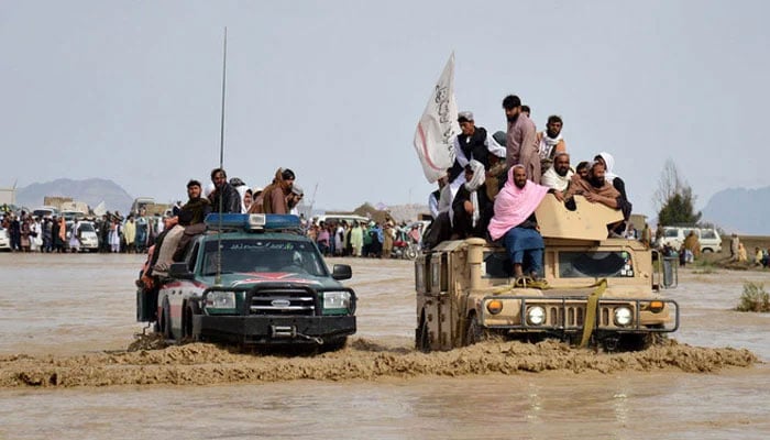 Afghan men sit atop military vehicles as they cross through a flooded area in Spin Boldak district of Kandahar province, after a flash flood following a heavy rainfall on April 13, 2024. — AFP