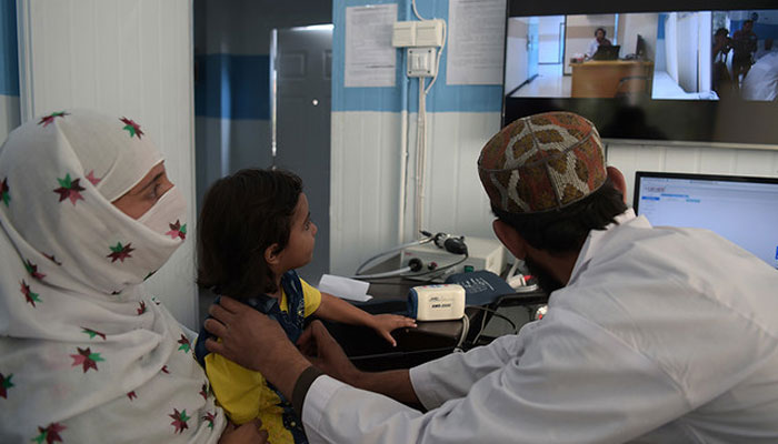 This photograph shows a Pakistani paramedic checking a child at a telemedicine online treatment centre in Pakistan. — AFP/File