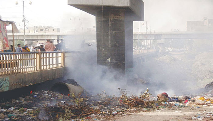 This picture shows Smoke billows from a burning pile of garbage dumped .—Online/File
