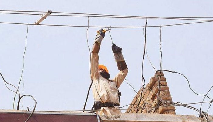 This image shows a man repairing an electric connection. — APP/File