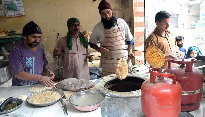 A vendor is seen busy making traditional bread (naan) at a tandoor in Lahore. — APP/File