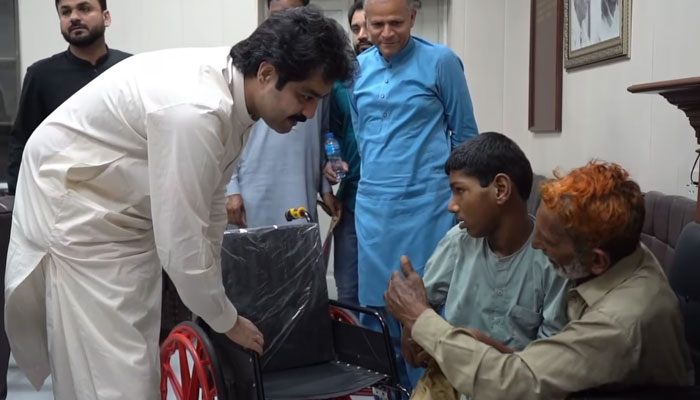 In this still, Minister for Social Welfare and Baitul Maal Sohail Shaukat Butt places Ali Hamza on a wheelchair on April 23, 2024. — Facebook/Social Welfare and Bait-ul-Maal Department, Government of the Punjab