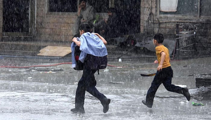 Children walk during rain on April 15, 2024. — APP