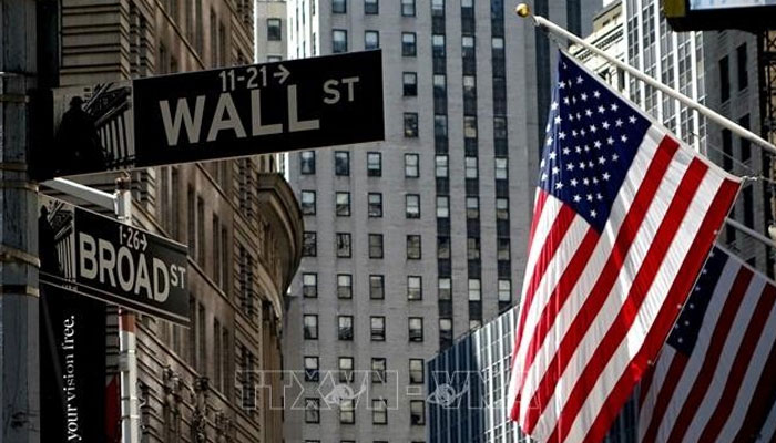 A representational image of a US flag pictured alongside a street sign reading Wall Street in the New York city. — AFP/File