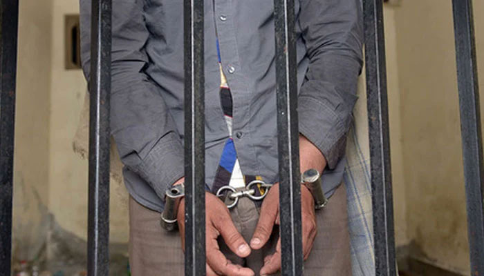 A representational image of a handcuffed person behind bars. — AFP/File