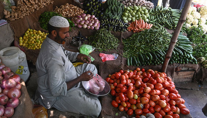 A vendor weighs vegetables for a customer at a local market in Lahore. — AFP/File
