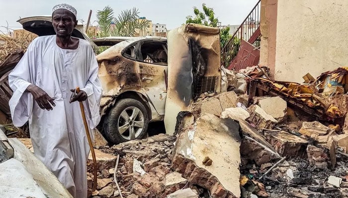 A man inspects damage as he walks through the rubble by a destroyed car outside a house that was hit by an artillery shell in the Azhari district in the south of Khartoum on June 6, 2023. — AFP/File