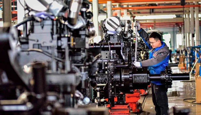 An employee works on a tractor production line at a factory in Weifang, eastern Shandong province, China, on March 1, 2024. — AFP