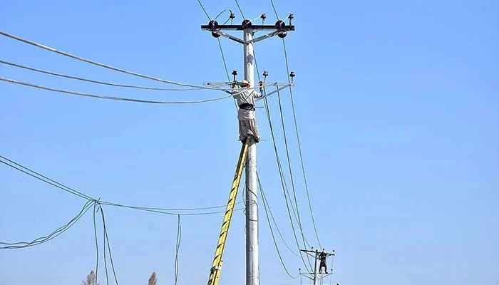 Workers seen on an electric pole in Islamabad, on October 26, 2023. — APP