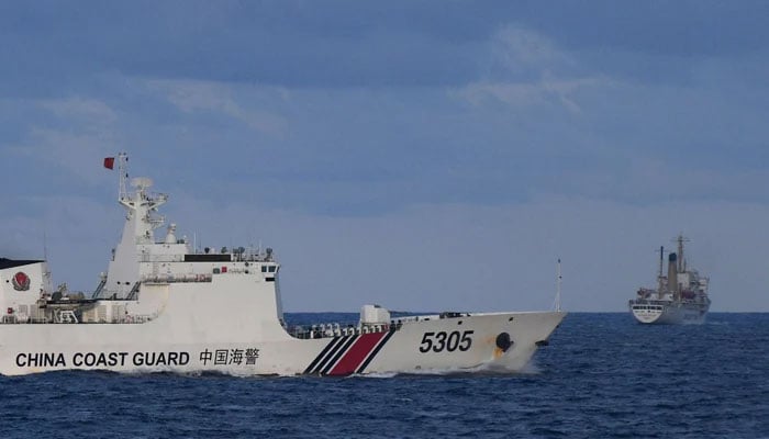 A Chinese Coast Guard ship sails near a Philippine vessel (R) that was part of a convoy of civilian boats in the disputed South China Sea on December 10, 2023. — AFP