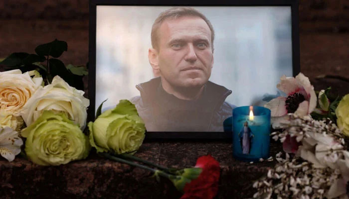 A portrait of Alexei Navalny, candles, and flowers are seen at a memorial in Paris on February 16, 2024. — AFP