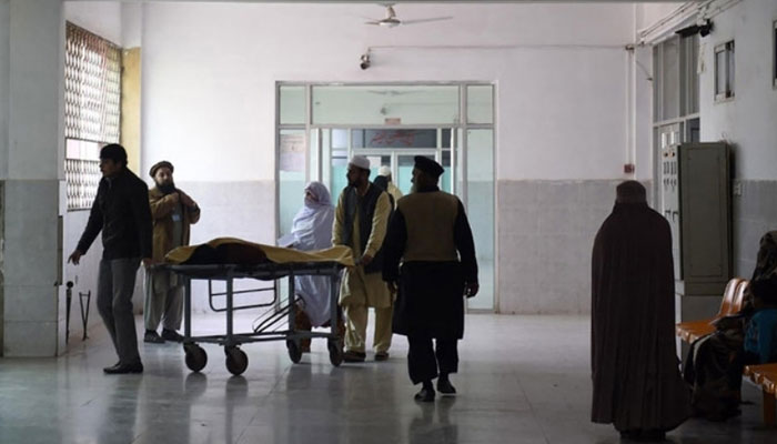 Relatives can be seen carrying an at a hospital. — AFP/File