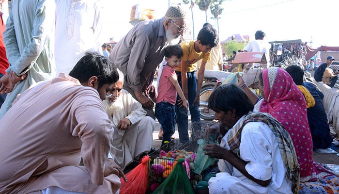 People purchase different birds from a vendor at the bird market in Karachi. — APP/File