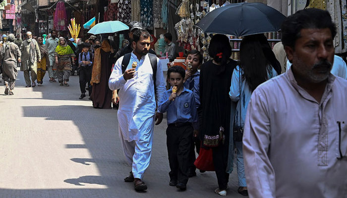 A representational image showing people walking along a market in Lahore on May 17, 2023. — AFP