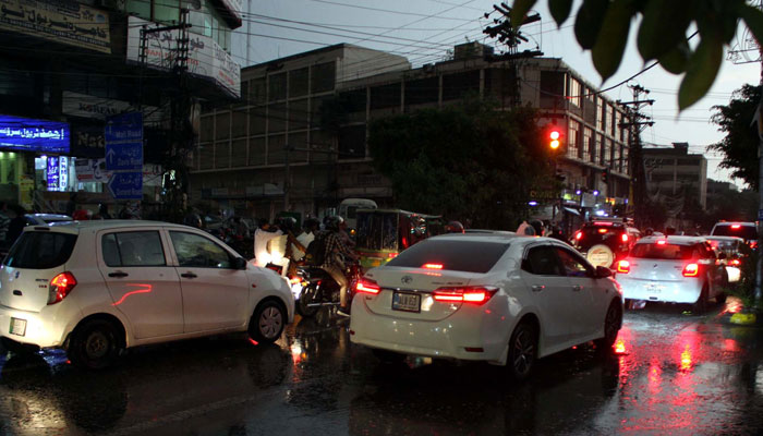 Commuters make their way to a road amid rain showers, at Shimla Hill in Lahore on Friday, April 26, 2024. — PPI