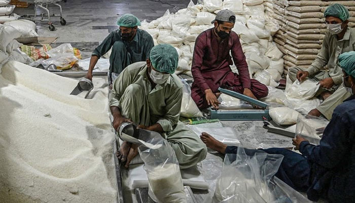 Workers prepare sugar bags at a warehouse in Pakistan. — AFP/File