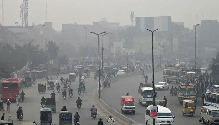 Commuters make their way through a busy street amid smoggy conditions in Lahore. — AFP/File