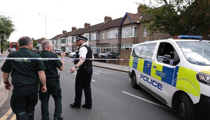 A police officer speaks to ambulance staff at a crime scene in Hainault, east of London on April 30, 2024. — AFP