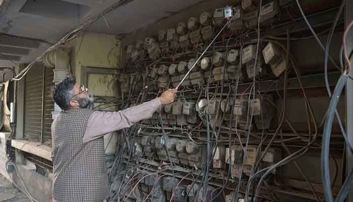 A Representational image of Pakistani employee of the state-run Islamabad Electric Supply Company (IESCO), takes a meter reading with his smartphone at a commercial building in Islamabad. — AFP