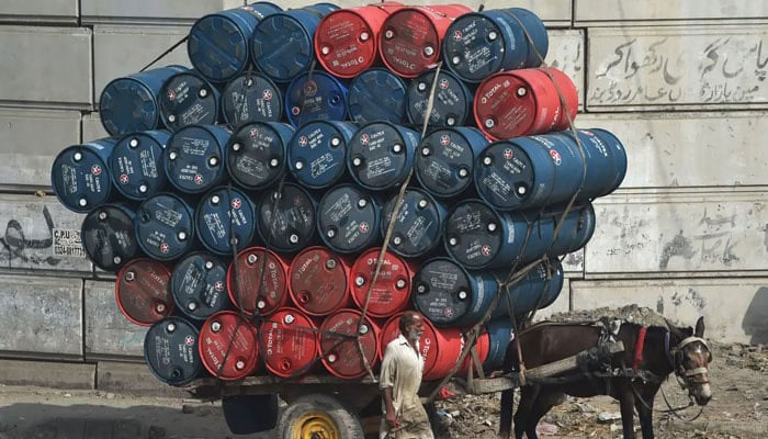 A man stands next to a horsecart laden with fuel drums on a street in Lahore. — AFP/File