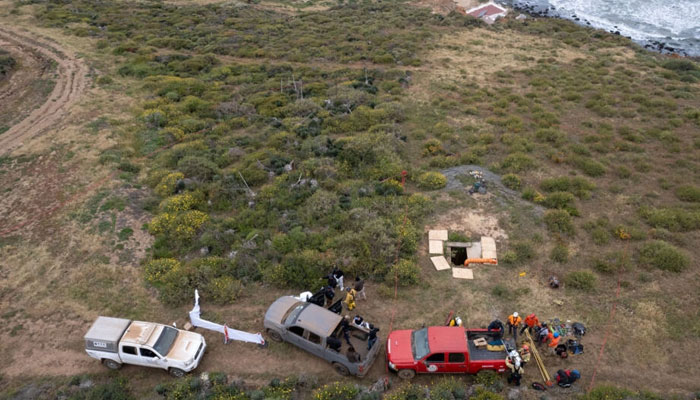 Three trucks with people around them on a cliff-top shaft in Mexicos Baja California. — AFP