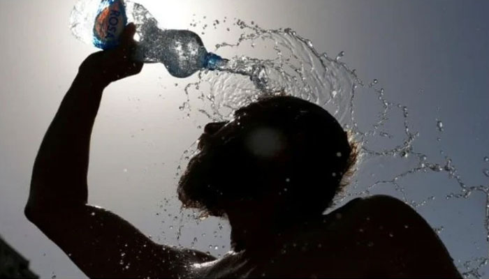 A man pours water on his face to cool off from the hot weather. — Reuters/ File