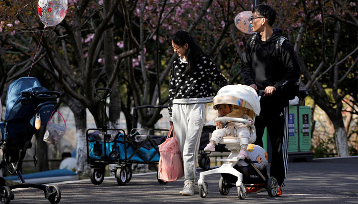 A parents pushes a stroller with a baby in a park in Shanghai, China, April 2, 2023. — Reuters