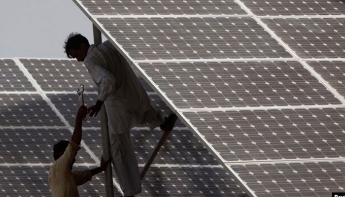 Technicians work on solar panel in power station at Hub, near Karachi. — Reuters/File