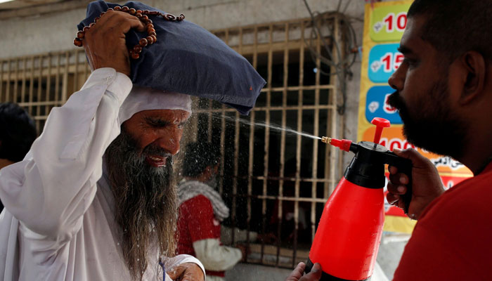 A man reacts as he receives a spray of cold water, to avoid the intense heatwave, at a stall, set up by a social welfare organisation. — Reuters/File