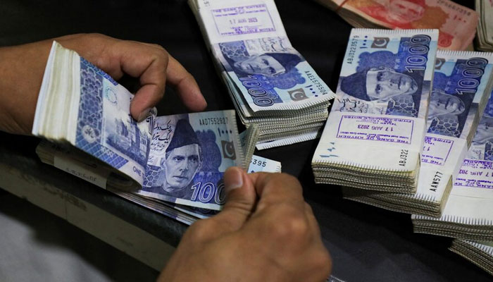 n employee counts Pakistani rupee notes at a bank in Peshawar on August 22, 2023. — Reuters