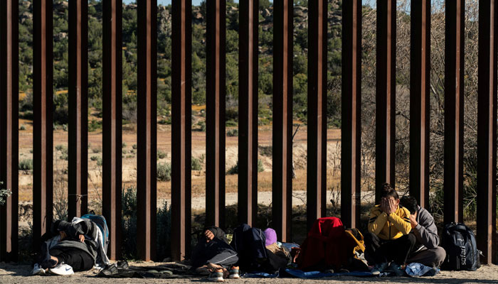 Asylum-seeking migrants from India wait by the border wall while waiting to be picked up by the U.S. Border Patrol after crossing the border from Mexico into the U.S. in Jacumba Hot Springs, California, U.S. April 27, 2024. — Reuters