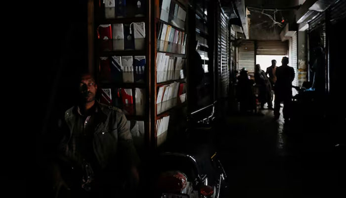 A man sits outside his shop during a power breakdown in Pakistan. — REUTERS/File